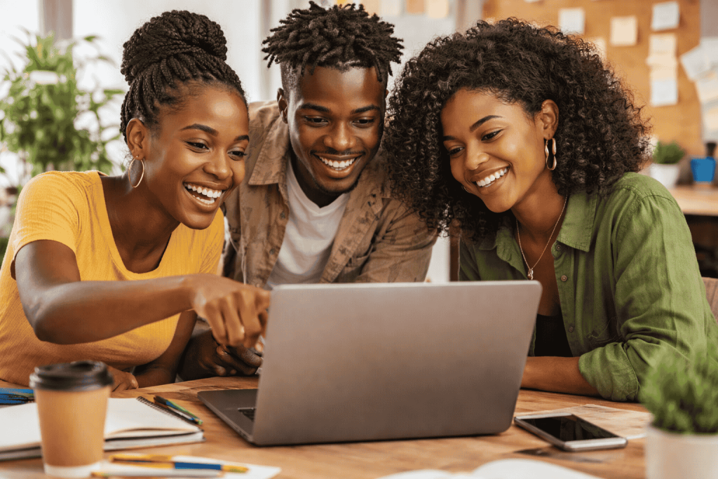 Young African creators collaborating with AI tools around a laptop